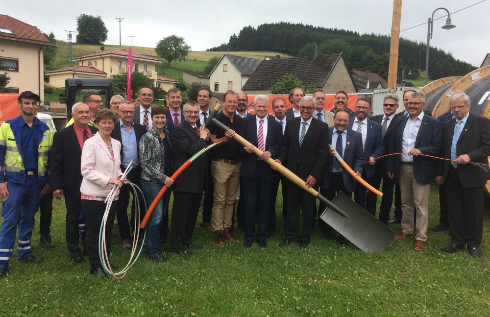 Landrat Dr. Alexander Saftig (Landkreis Mayen-Koblenz, vorderer Reihe 3. v. l.), Bürgermeister von Mendig Jörg Lempertz (vordere Reihe 4. v. r., mit einer Hand am Spaten), Manfred Henning (aconium GmbH, vordere Reihe mittig), Innenmi-nister Roger Lewentz (Ministerium des Innern und für Sport Rheinland-Pfalz, vordere Reihe 4. v. r. mit beiden Händen am Spaten), Verbandsgemeindebürgermeister der Vordereifel Alfred Schomisch (vordere Reihe 3. v. r.) beim symbolischen Spatenstich für den Landkreis Mayen-Koblenz in Siebenbach am 19.06.2018. Foto: aconium GmbH